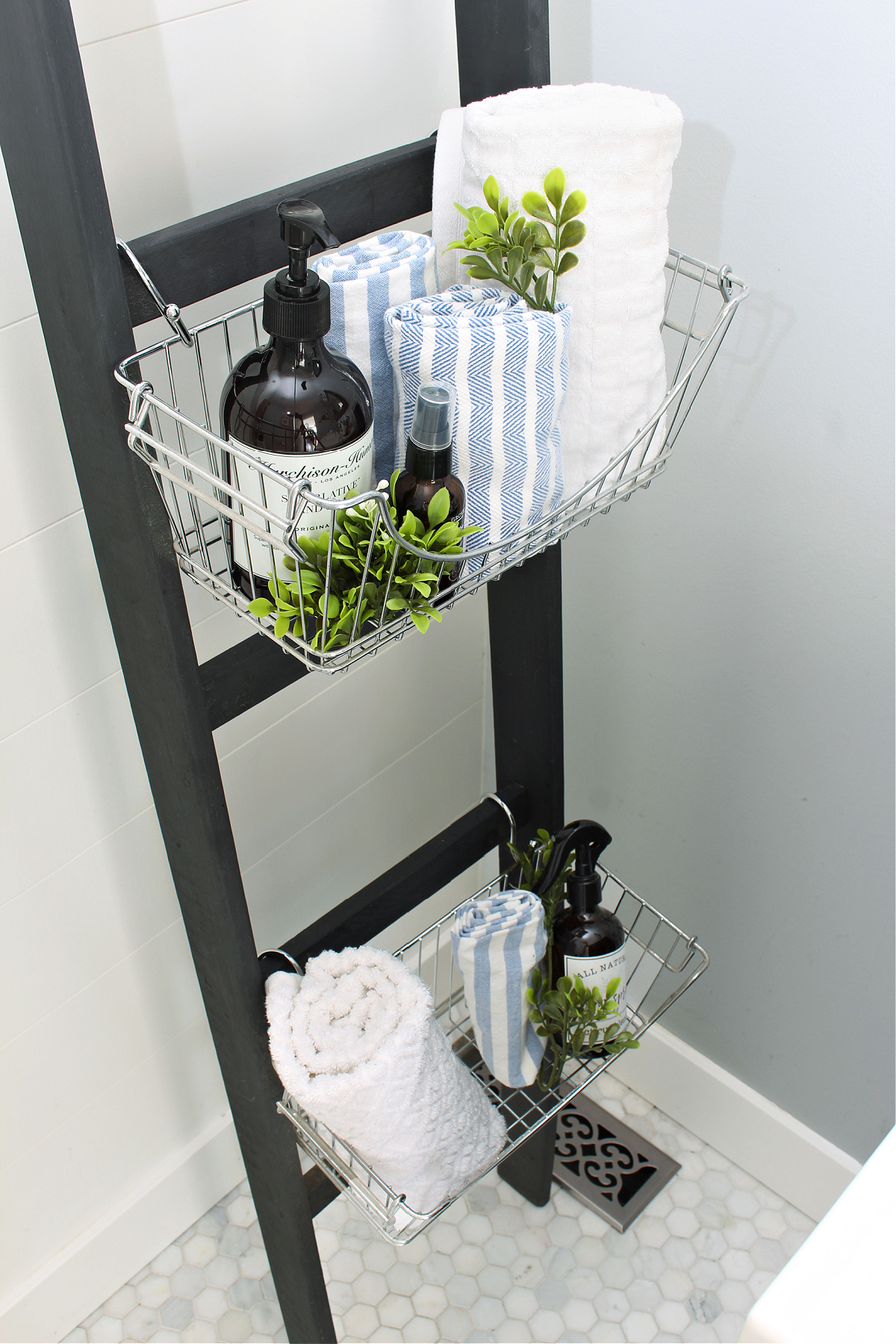 Black DIY bathroom storage ladder with wire baskets.