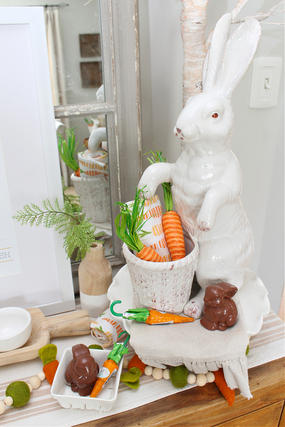 Easter sideboard decorated with white bunnies and carrots.