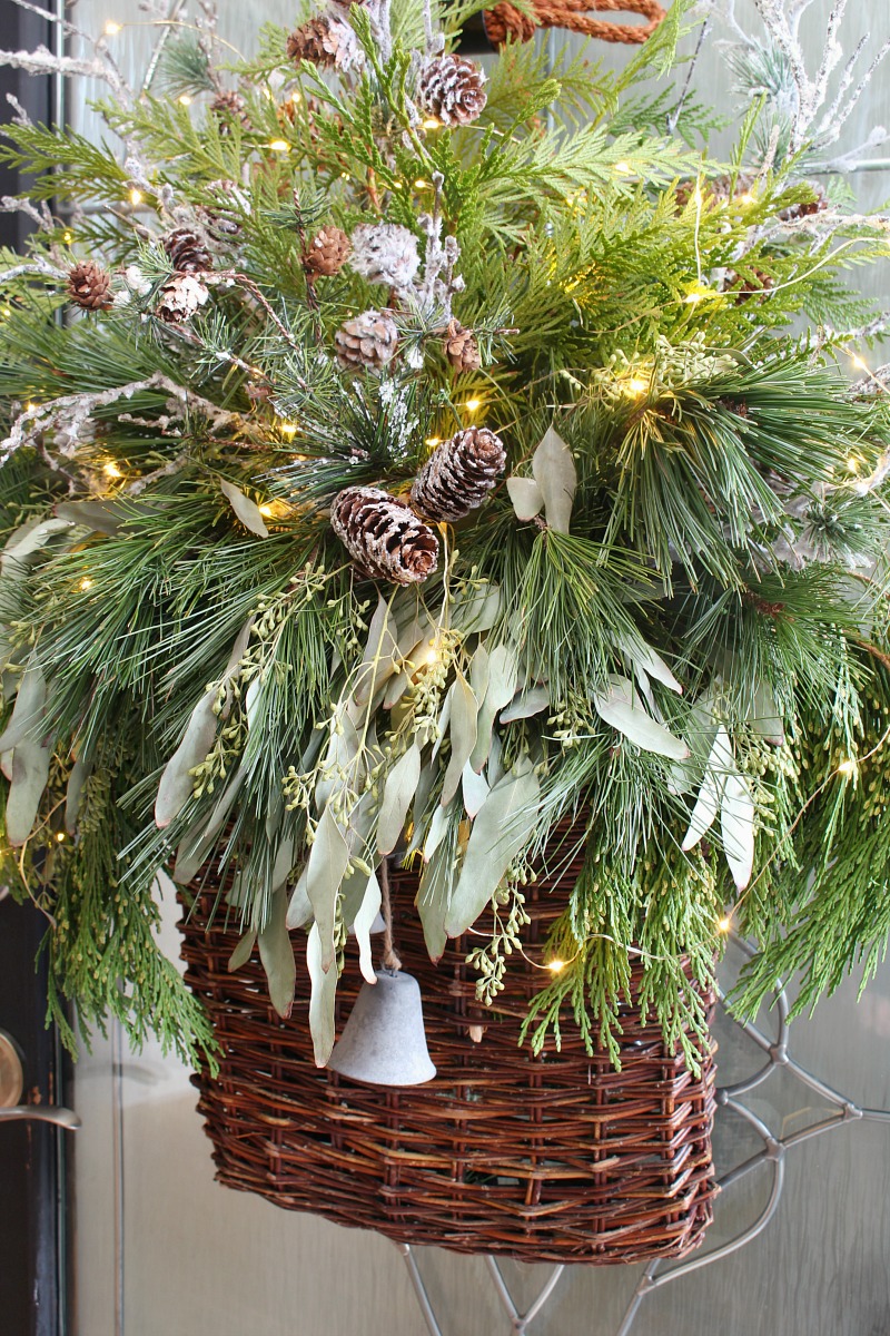Christmas basket wreath with fresh greenery and fairy lights.