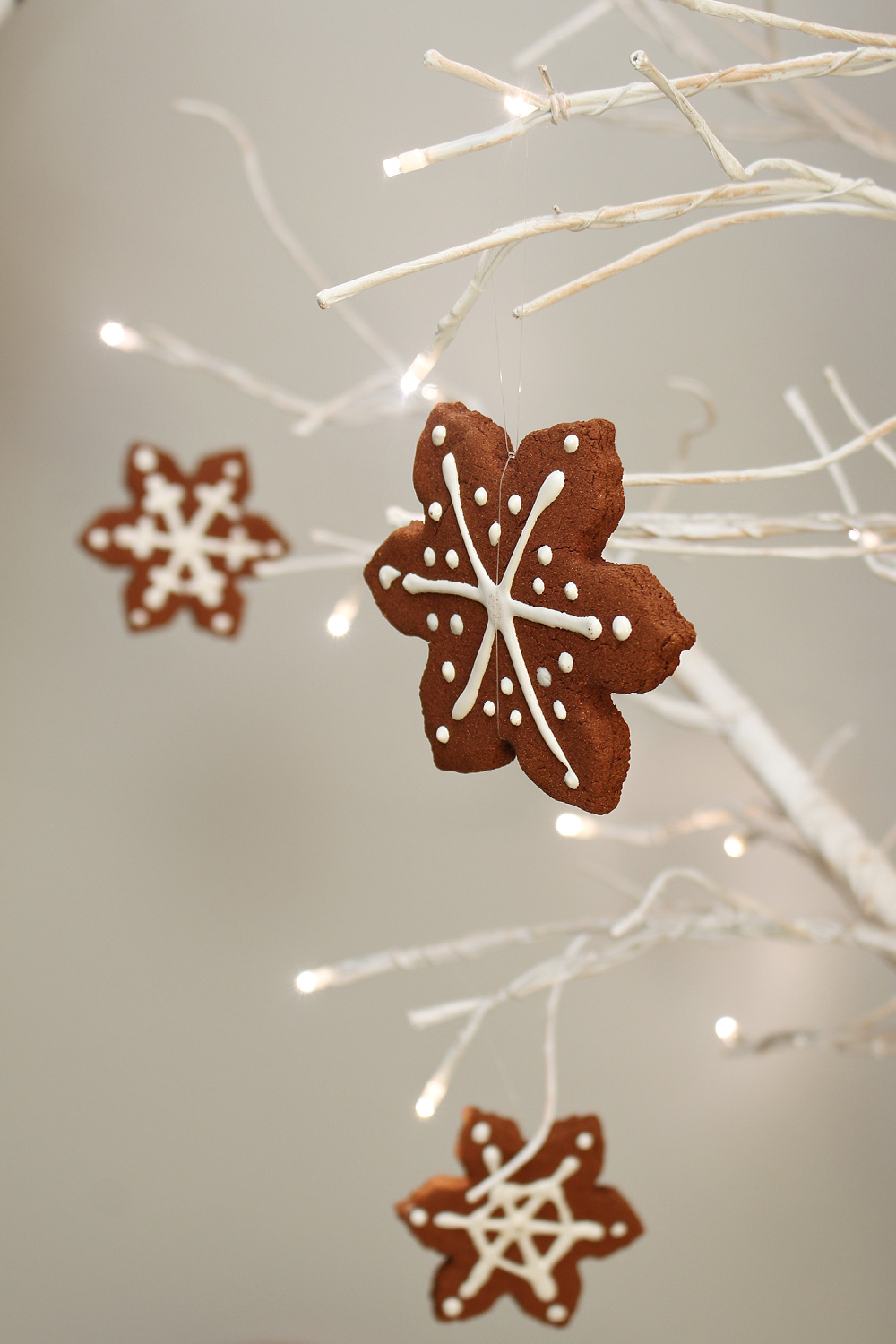 Faux gingerbread snowflakes hanging from a lighted tree.