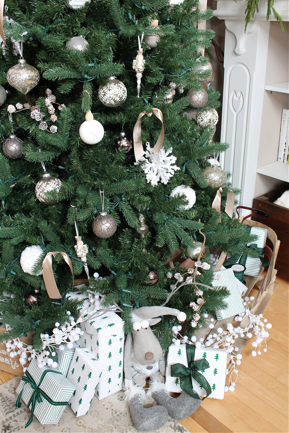 Christmas tree decorated with presents wrapped in green and white.