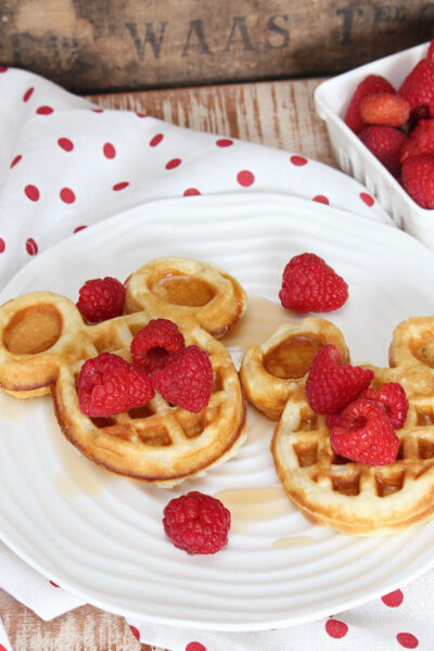 Cute mickey waffles with raspberries and syrup.