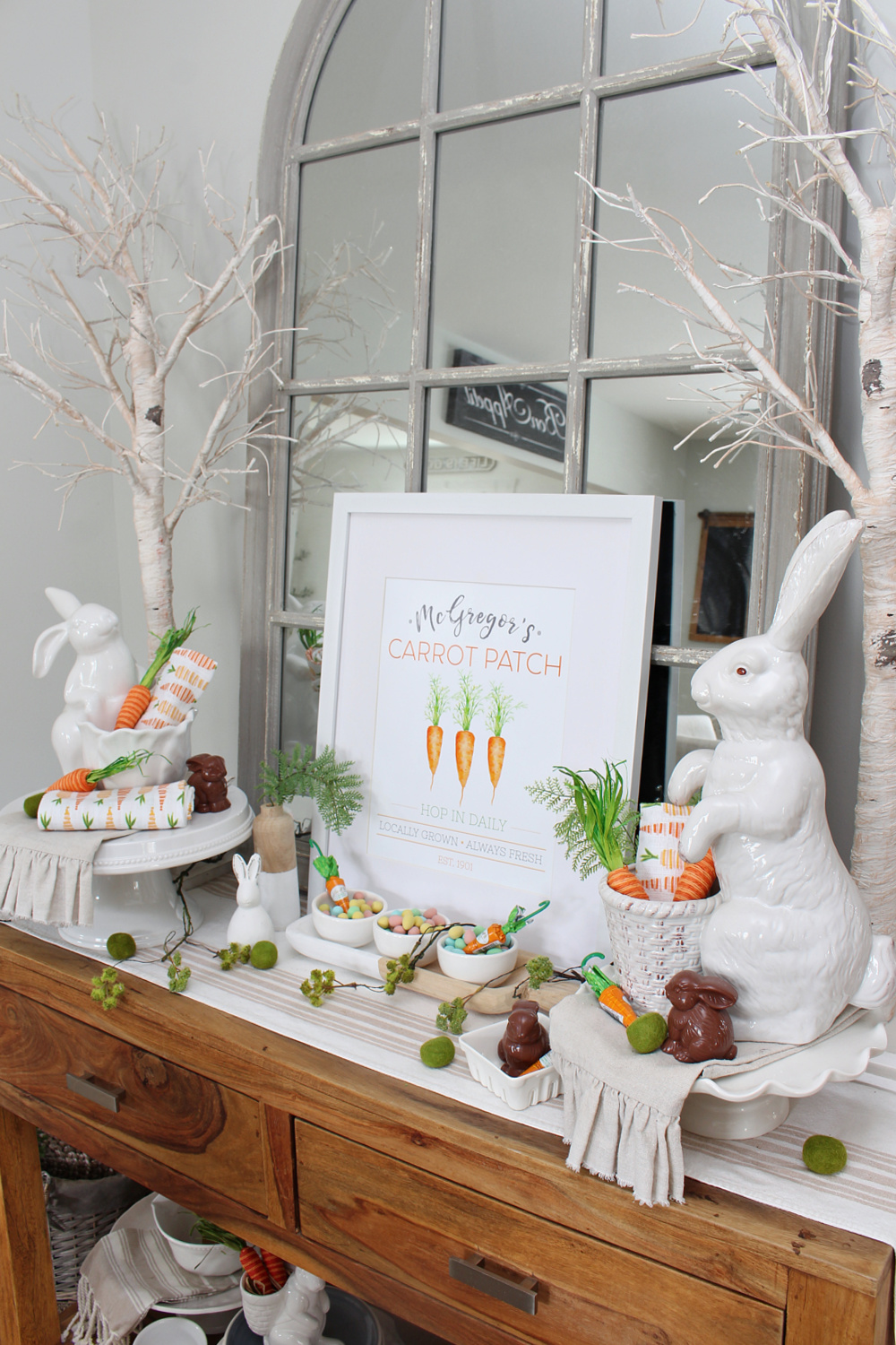 Dining room sideboard decorated for spring with white bunnies and carrots.