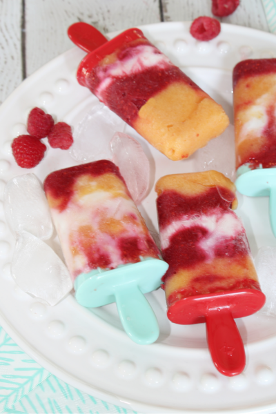 Raspberry peach yogurt popsicles on a plate with ice.